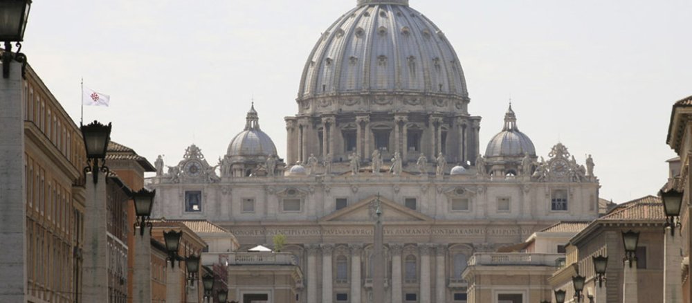 Front des Petersdoms mit der Kuppel in der Mitte, im Vordergrung die Straße Via della Conciliazione.