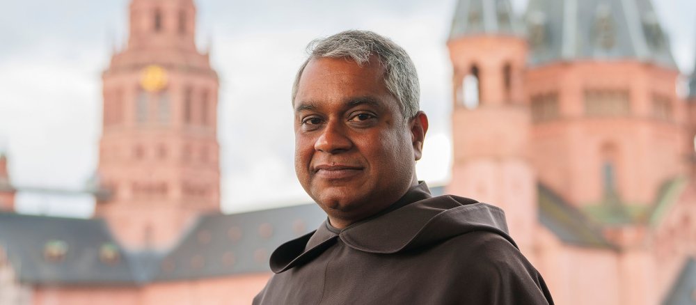 Joshy George Pottackal, ernannter Weihbischof in Mainz, steht auf einer Dachterasse des Erbacher Hof, Tagungszentrum und Gästehaus des Bistums Mainz, mit Blick auf den Dom.