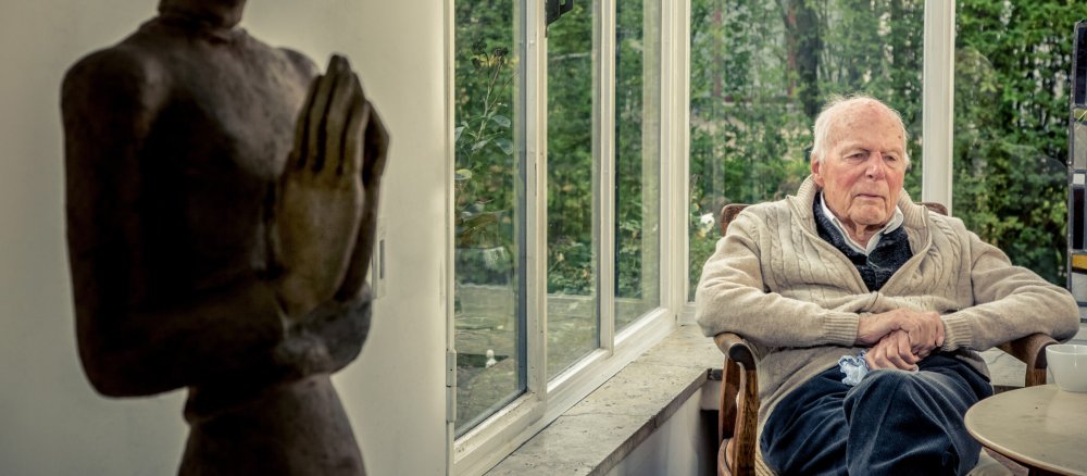Der Architekt Gottfried Böhm im Wintergarten seines Hauses in Köln. Im Vordergrund steht die Skulptur einer Frau mit gefalteten Händen.