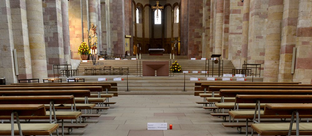 Im Durchgang und im Altarrraum des Speyrer Doms sind rote Grablichter und Namensschilder aufgestellt.