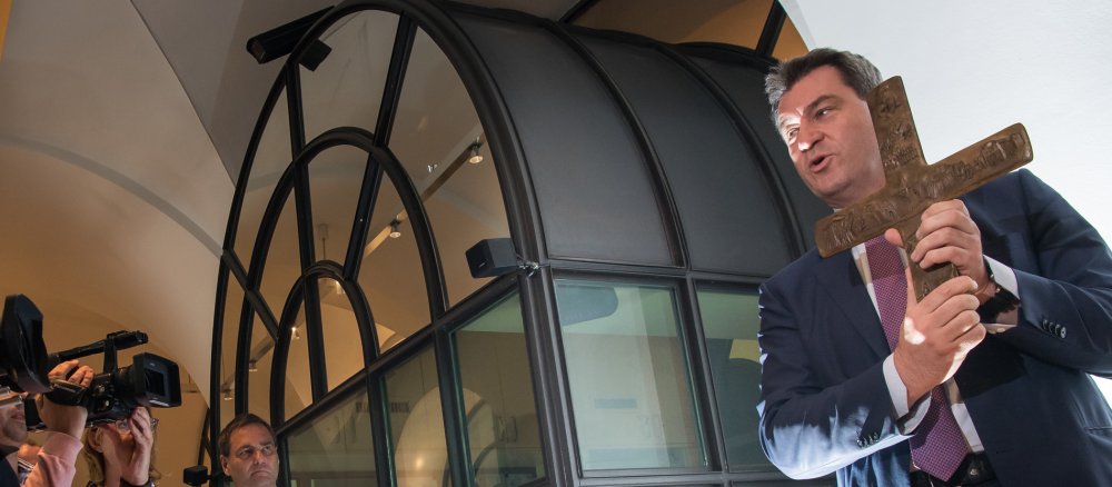 Markus Söder, Bayerischer Ministerpräsident (CSU), hängt ein Kreuz im Eingangsbereich der bayerischen Staatskanzlei auf.