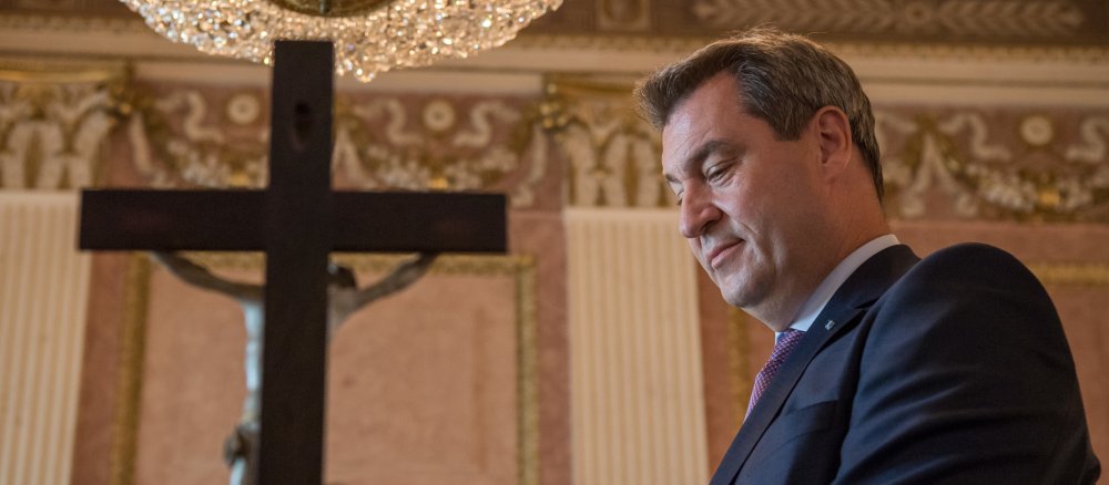 Bayerns Ministerpräsident Markus Söder steht vor einem Kruzifix.