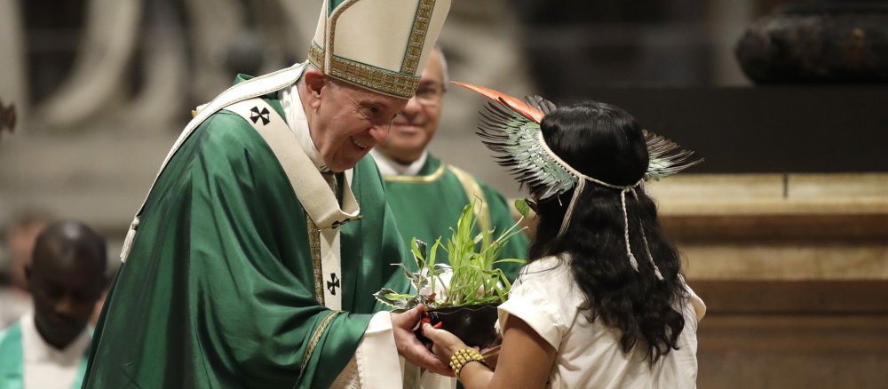 Eine Indigene überreicht Papst Franziskus bei der Abschlussmesse der Amazonas-Synode eine Pflanze.