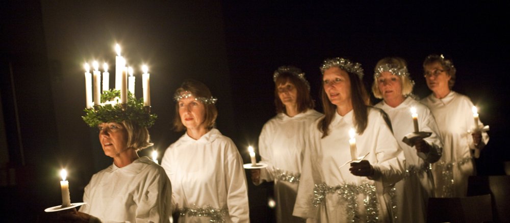 Sechs Frauen in weißen Gewändern und mit Kerzen, die erste in der Reihe trägt zudem einen Kerzenkranz auf dem Kopf.