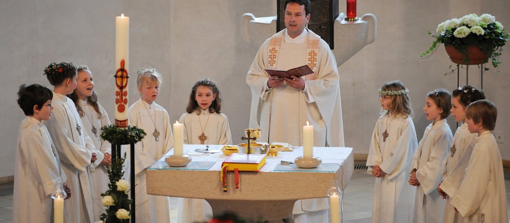 Kommunionkinde stehen im Kreis um den Altar herum