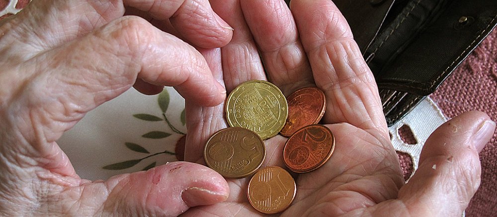 Eine arme Frau zählt Geld in ihrer Hand.