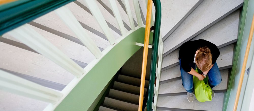 Eine Frau sitzt alleine und verzweifelt auf einer Treppenstufe