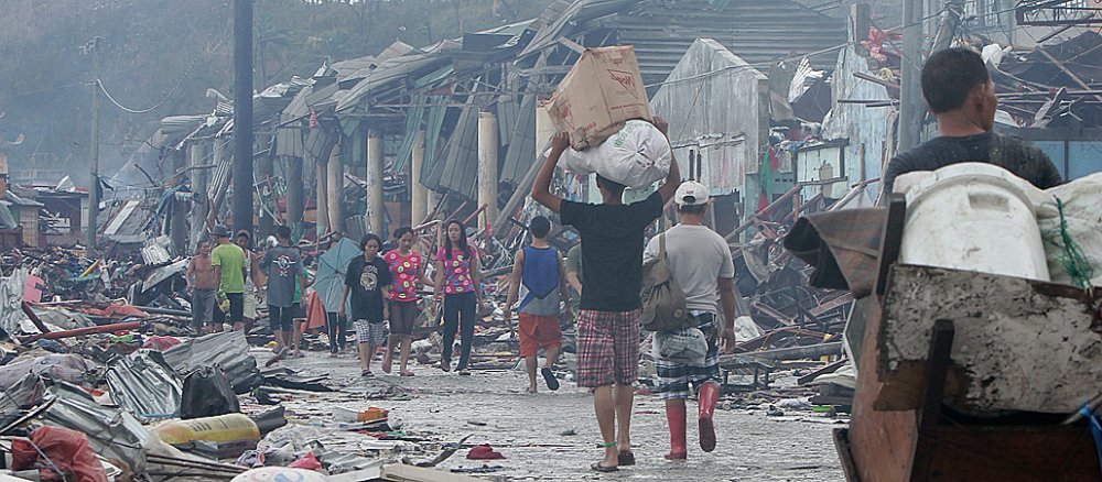 Opfer des verheerenden Taifuns "Haiyan" auf den Philippinen laufen durch eine völlig zerstörte Ortschaft.