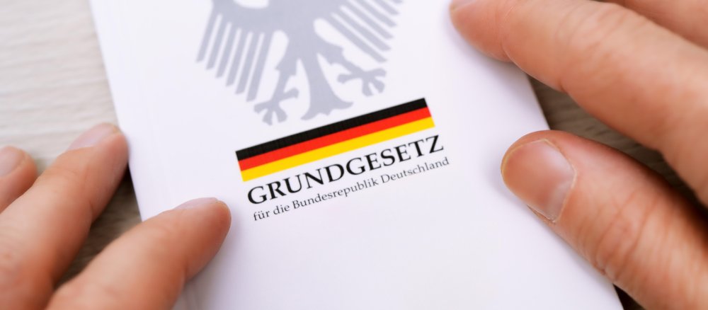 Finger berühren eine gedruckte Ausgabe des Deutschen Grundgesetzes