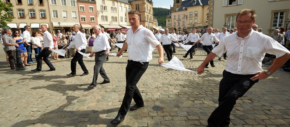 Die Teilnehmer der Springprozession in Echternach springen zu Polkamelodien in Reihen durch die Straßen der Stadt.