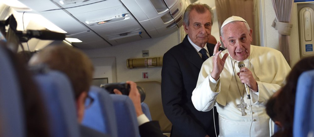 Franziskus in einem Flugzeug mit einem Mikrophon vor Journalisten