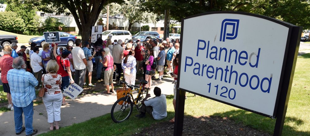 Abtreibungsgegner stehen vor einem Schild von "Planned Parenthood".
