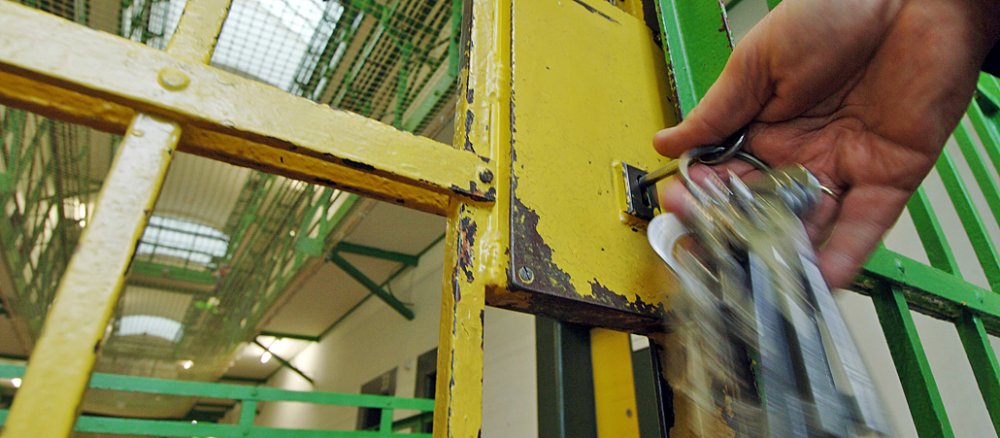 Ein Beamter schließt eine Gittertür mit seinem Schlüsselbund in einer Justizvollzugsanstalt.
