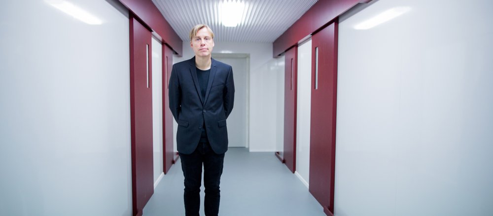 Der Künstler Gregor Schneider steht in einem Raum mit vier roten Türen.