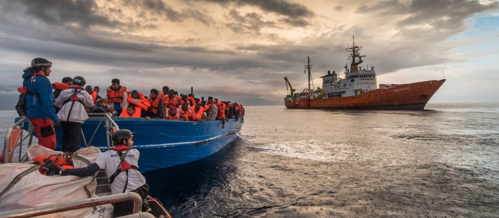 Helfer retten Flüchtlinge von einem Holzboot vor der libyschen Küste