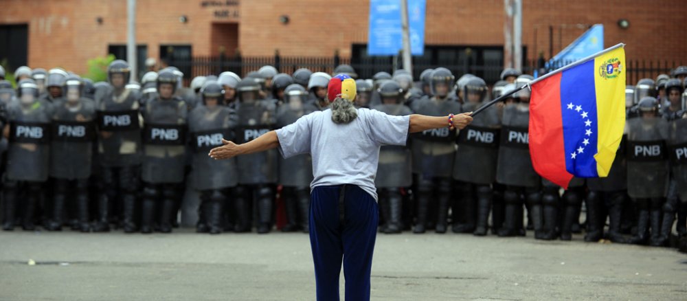 Bei einem Studentenprotest in Venezuela steht eine Demonstrantin der Polizei gegenüber.