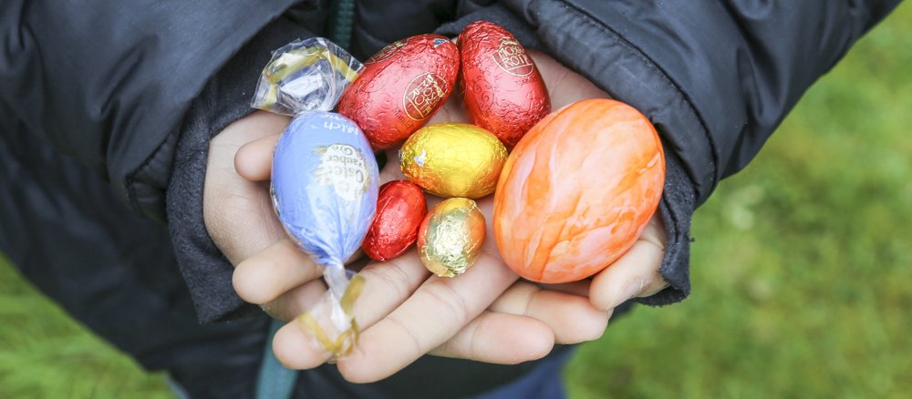 Ein Kind hält in den Händen gefundene bunte Ostereier.