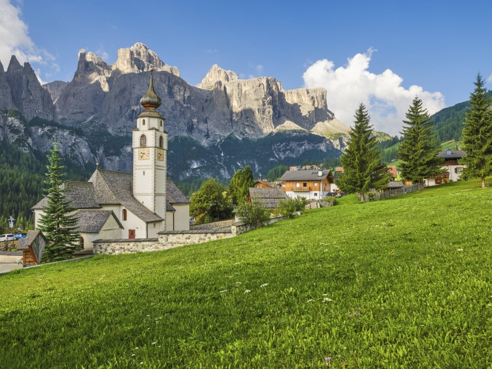 Eine Dorfkirche vor einem Bergwand.
