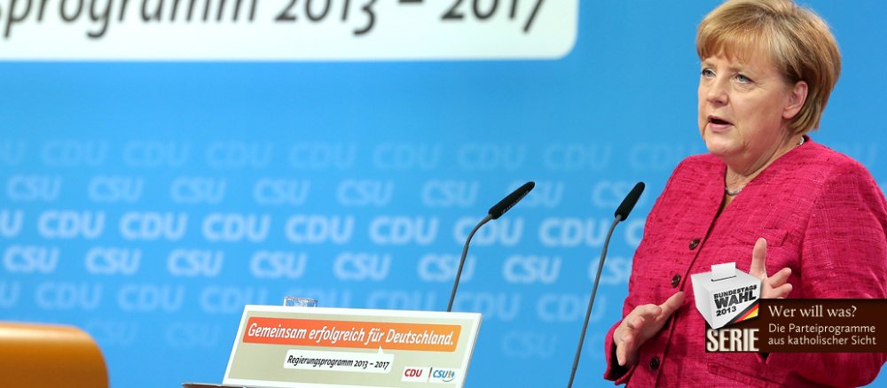 Bundeskanzlerin Angela Merkel steht an einem Rednerpult, sie spricht und gestikuliert.