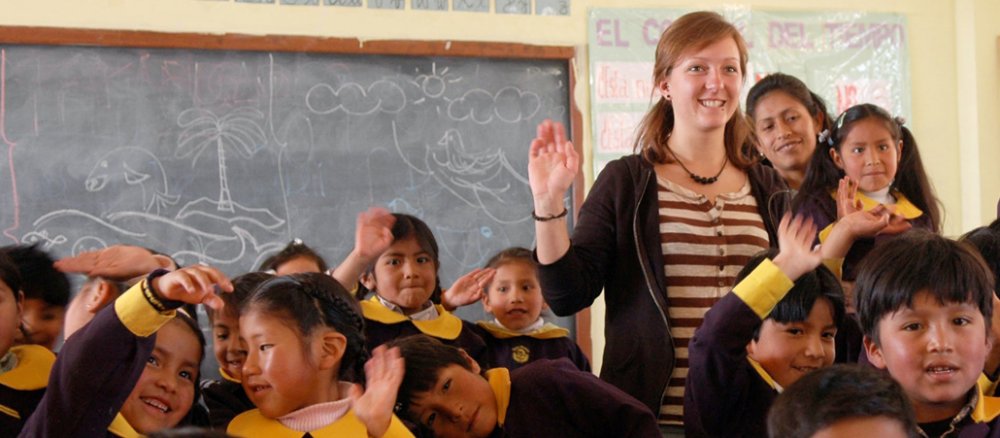 Eine junge Frau in einer Schule zwischen boliviansichen Kindern.