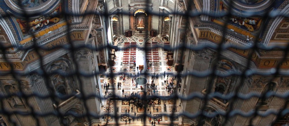 Blick durch Gitter auf das Innere des Petersdoms.
