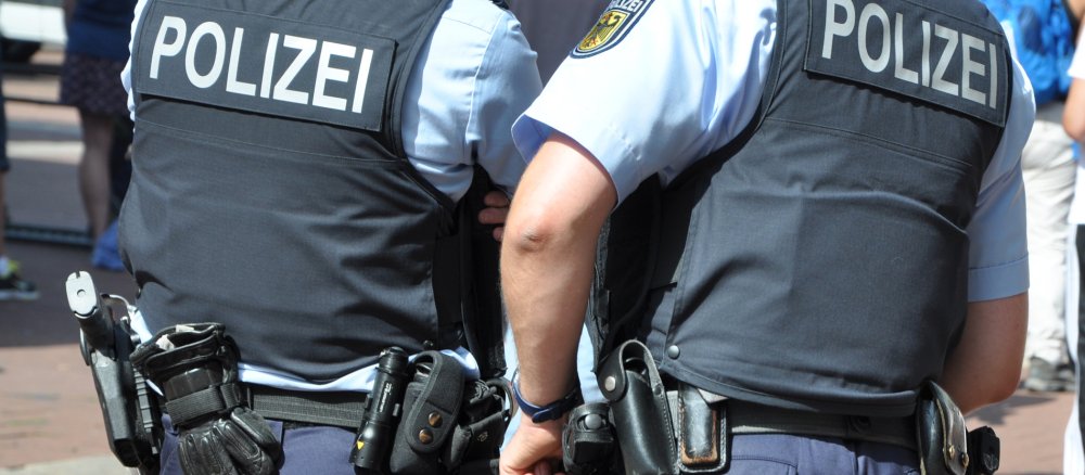 Zwei Polizeibeamte mit Sicherheitswesten am Rande eines Einsatzes.