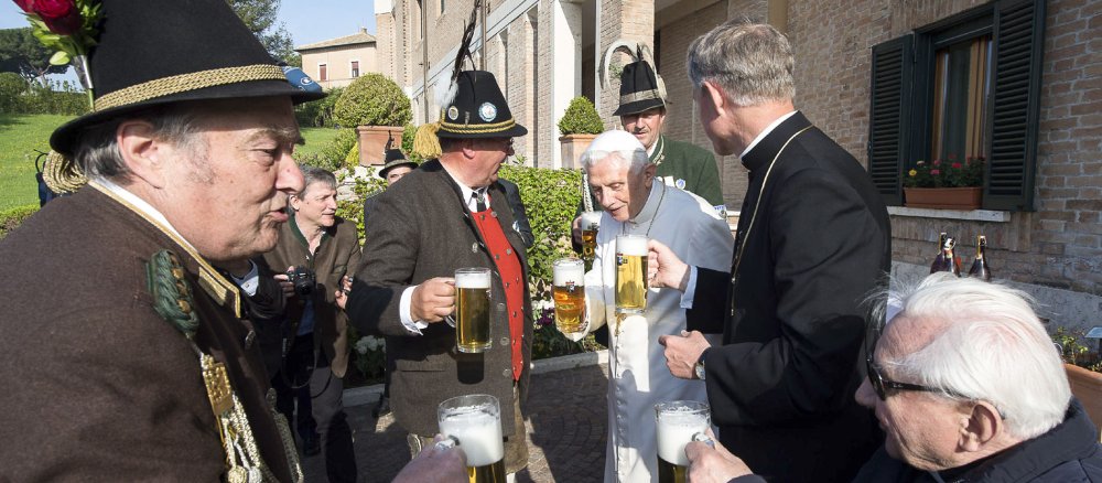 Benedikt XVI. stößt mit einer Trachtengruppe auf seinen 88. Geburtstag an.