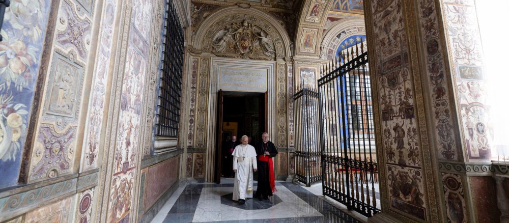 Papst Leo XIV. geht mit Kardinal Pietro Parolin durch einen mit Fresken geschmückten Gang