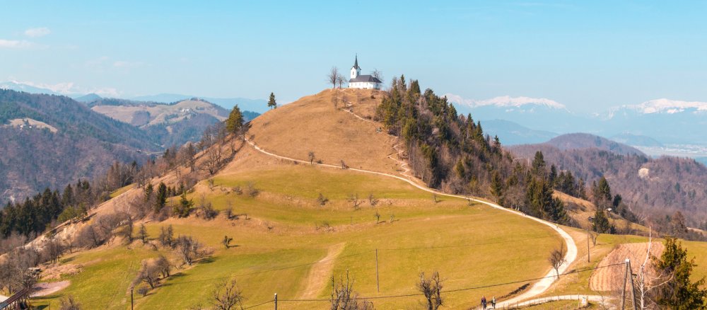 Eine geschlungener Weg führt zu einer kleinen Kapelle auf dem Gipfel eines Hügels.