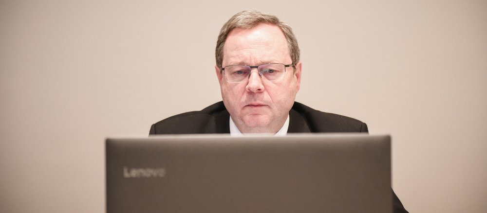 Bischof Georg Bätzing schaut auf einen Laptop-Bildschirm