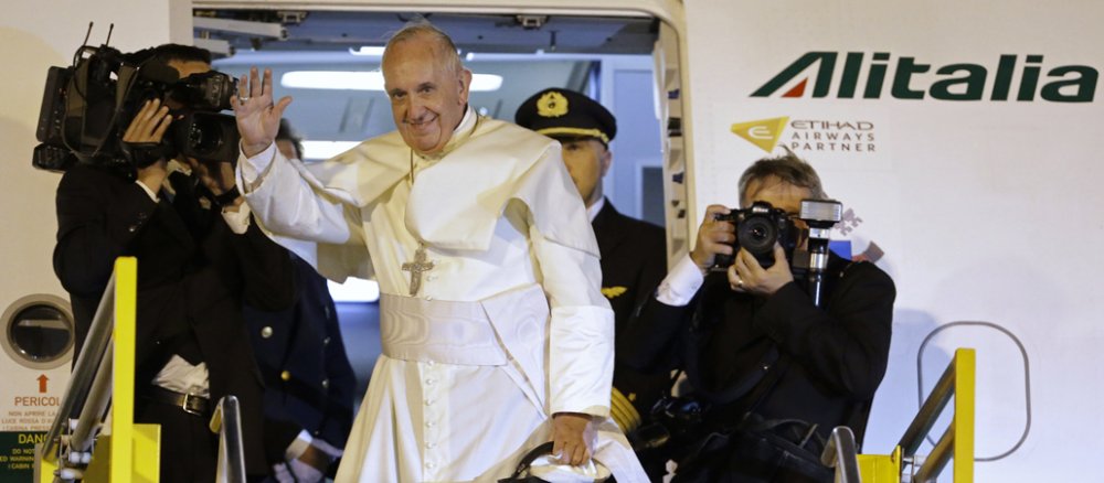 Papst Franziskus winkt während er in ein Flugzeug steigt.