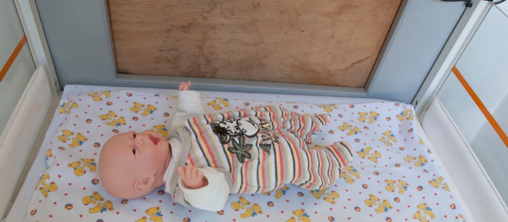 Eine Babypuppe liegt als Demonstrationsobjekt in einem Wärmebett im Innenraum der Babyklappe eines Klinikums in Neukölln.