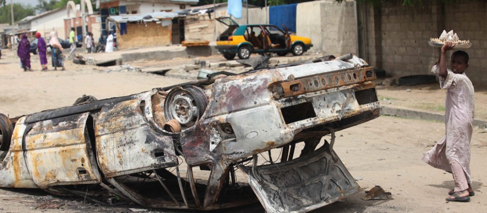 Nach Kämpfen mit Boko Haram läuft ein nigerianischer Junge an einem ausgebrannten Auto in Maiduguri vorbei.