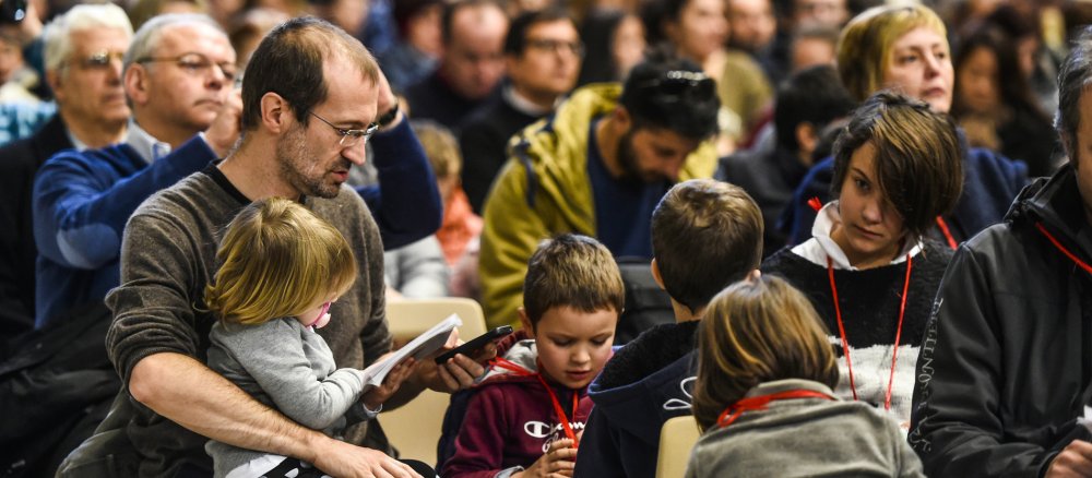 Eine Familie mit Kindern während eines Gottesdienstes im Petersdom.