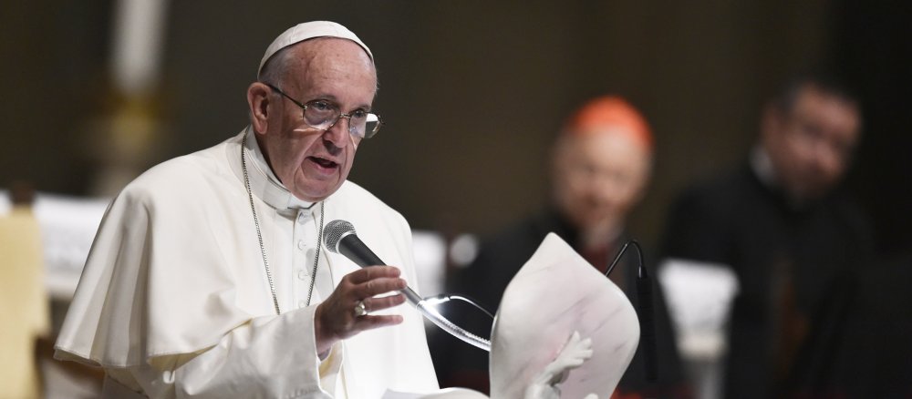 Papst Franziskus steht am Rednerpult und spricht mit ernsthaften Blick.