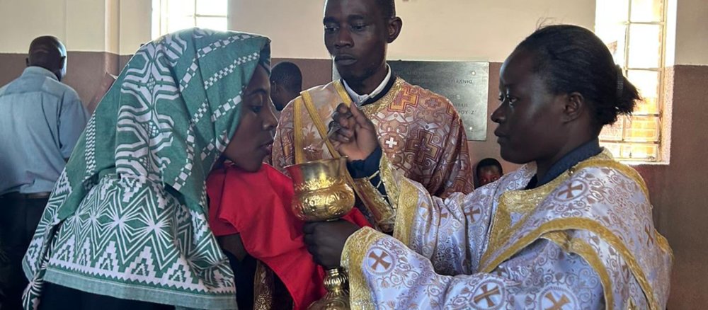 Orthodox deacon Angelic Molen gives communion to a woman