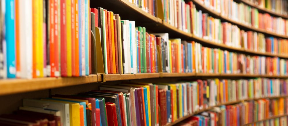 Many books stand on shelves in a library