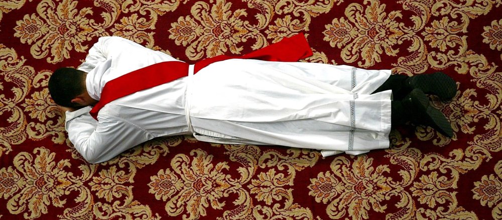 Ein Kandidat liegt während seiner Priesterweihe auf dem Boden.