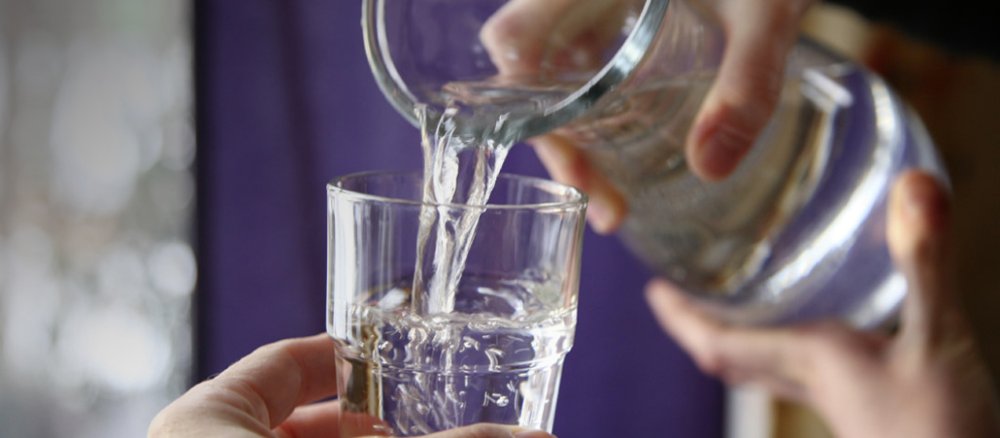 Wasser wird aus einer Karaffe in ein Glas geschüttet.