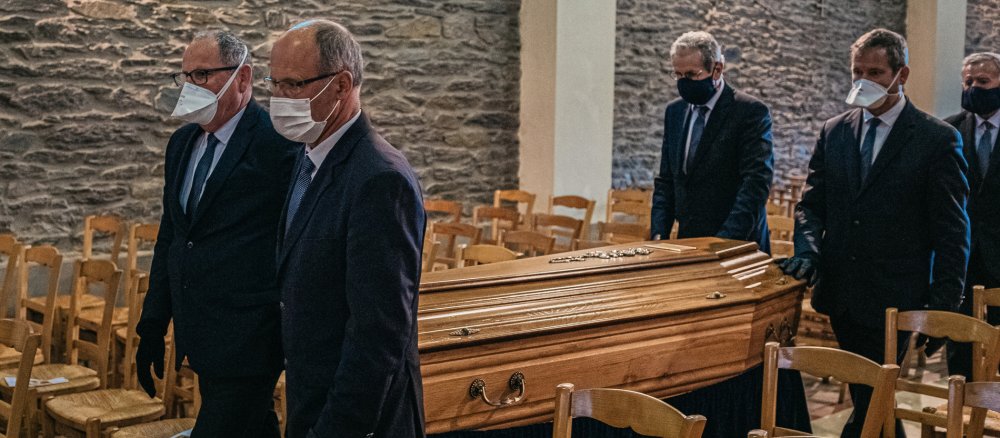 Männer mit Mundschutz tragen einen Sarg in die Kirche