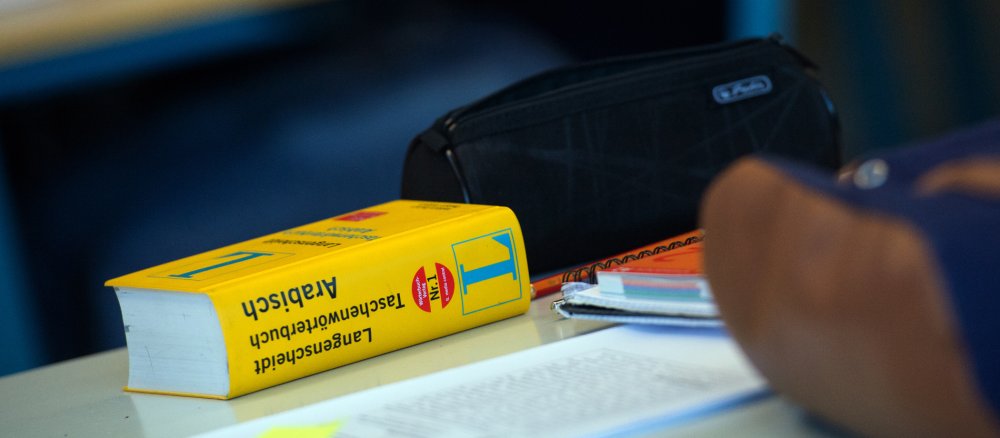 Auf einem Tisch liegt ein Wörterbuch "Arabisch"