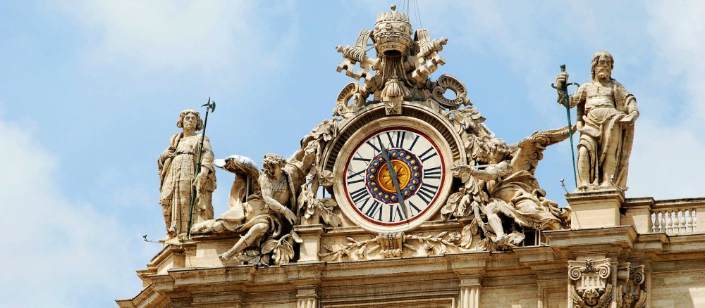 Eine der beiden Uhren auf der Monumentalfassade des Petersdomes im Vatikan.