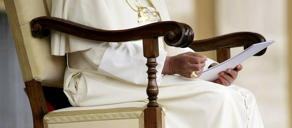 Der Papst sitzt auf einem Stuhl.