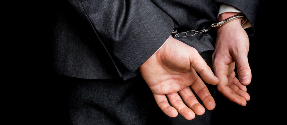 The handcuffed hands of a man behind his back.