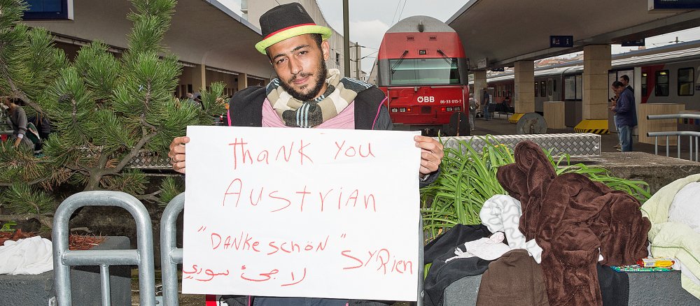 Syrischer Flüchtling hält Schild mit Aufschrift "Thank you, Austrian"