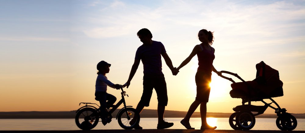 Familie im Gegenlicht eines Sonnenuntergangs am See.