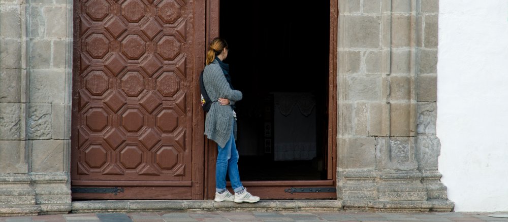 Eine Frau lehnt sich an eine Kirchentür