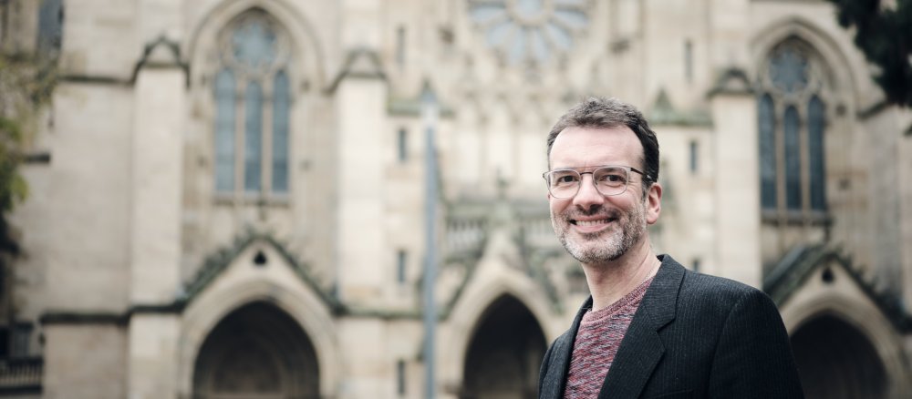 Kurator Sebastian Schmid steht vor der Kirche "St. Maria als"