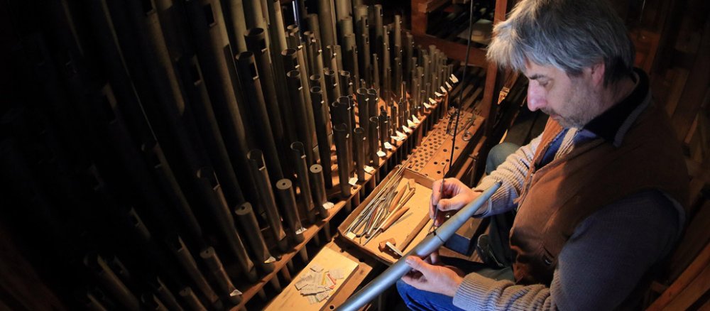 Ein Orgelbauer repariert eine Orgel.
