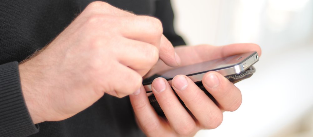 Ein Mann tippt auf sein Smartphone.